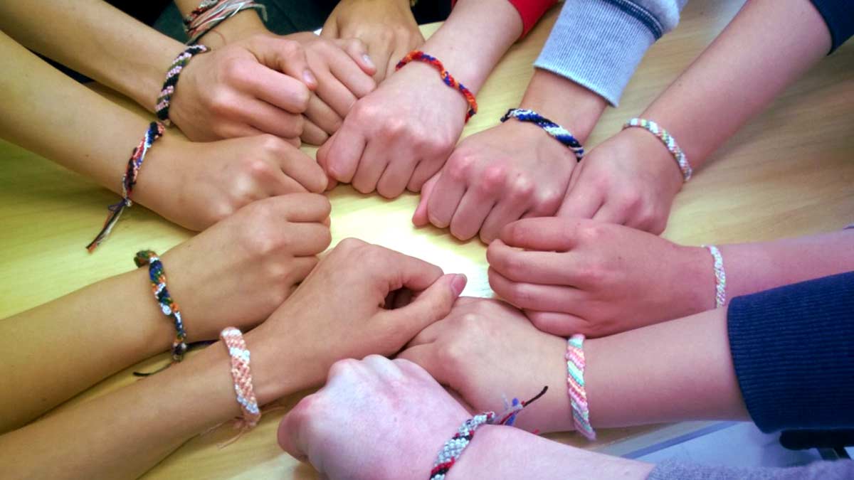 Joukko käsiä joissa on ystävyysrannekkeet.