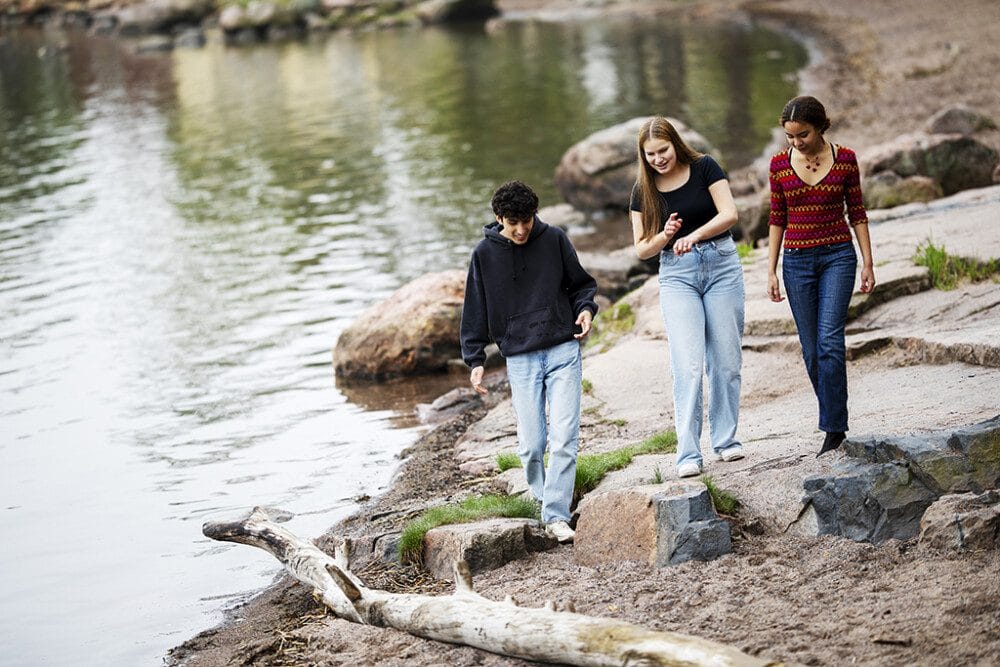 Kolme nuorta kävelee rannalla meren rannassa.