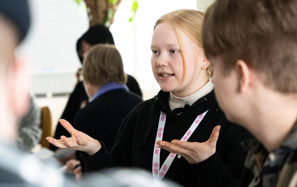 Kuvassa nuori puhumassa muille nuorille. Taustalla näkyy ihmisiä.