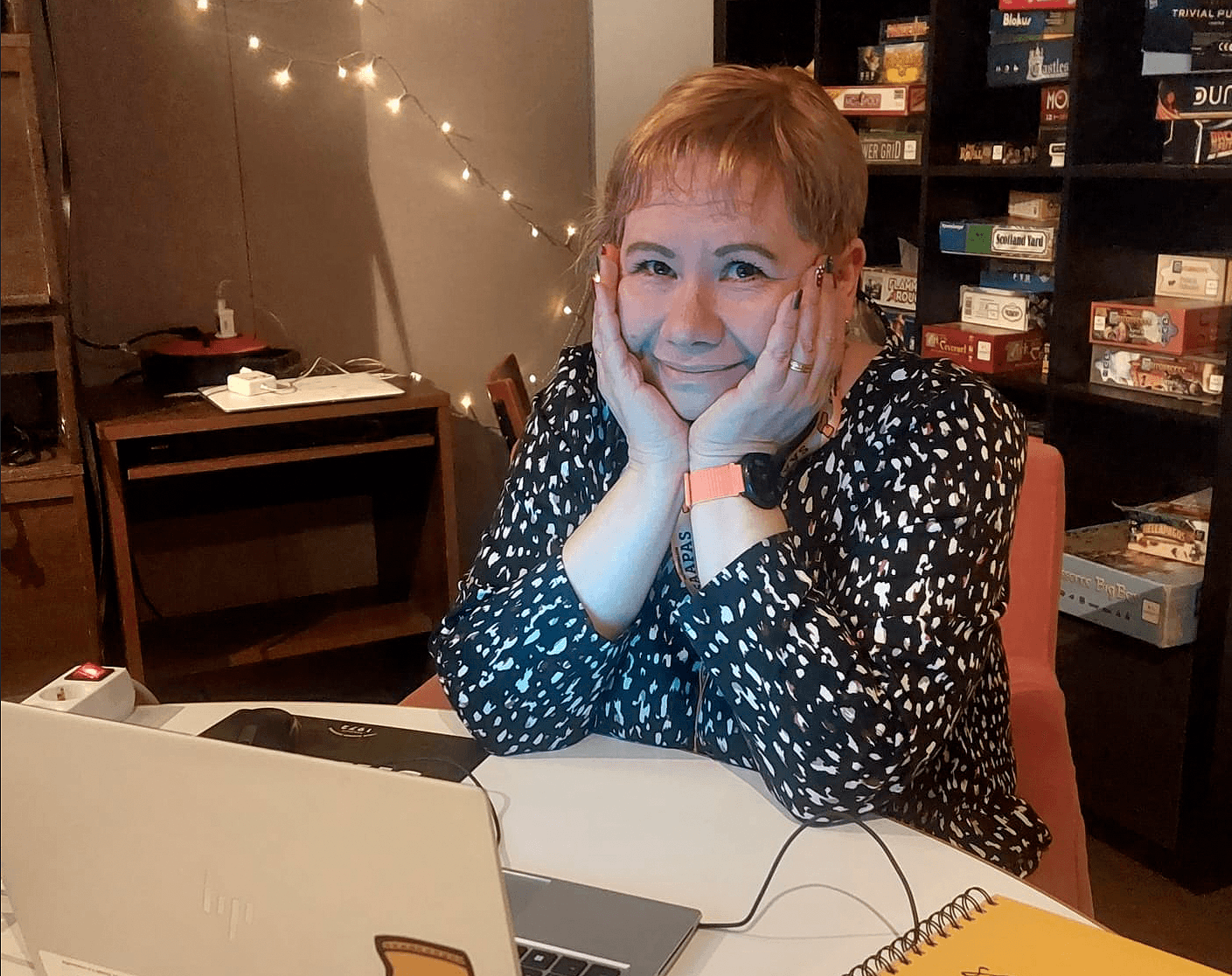 Naisoletettu henkilö istuu tietokoneen edessä ja hymyilee.