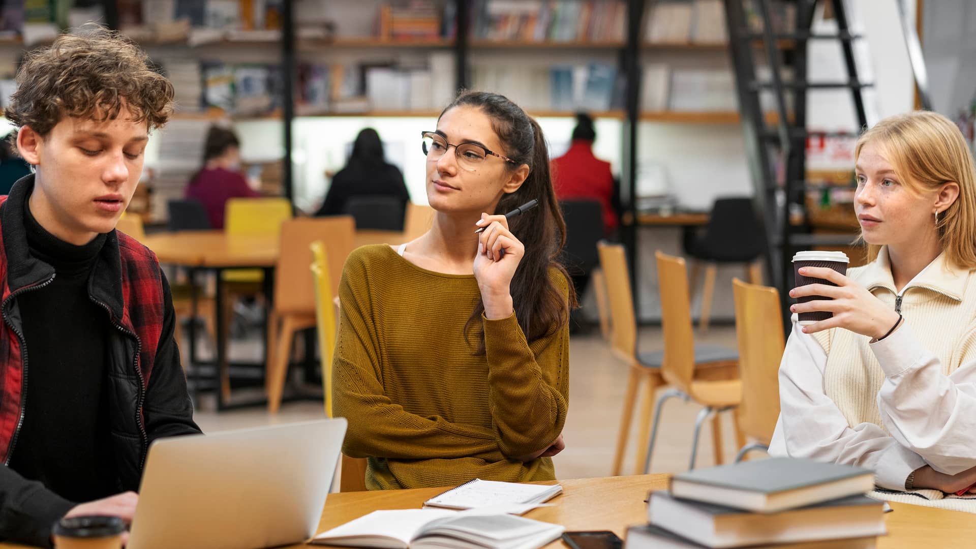 Kolme nuorta istuvat pöydän ääressä.