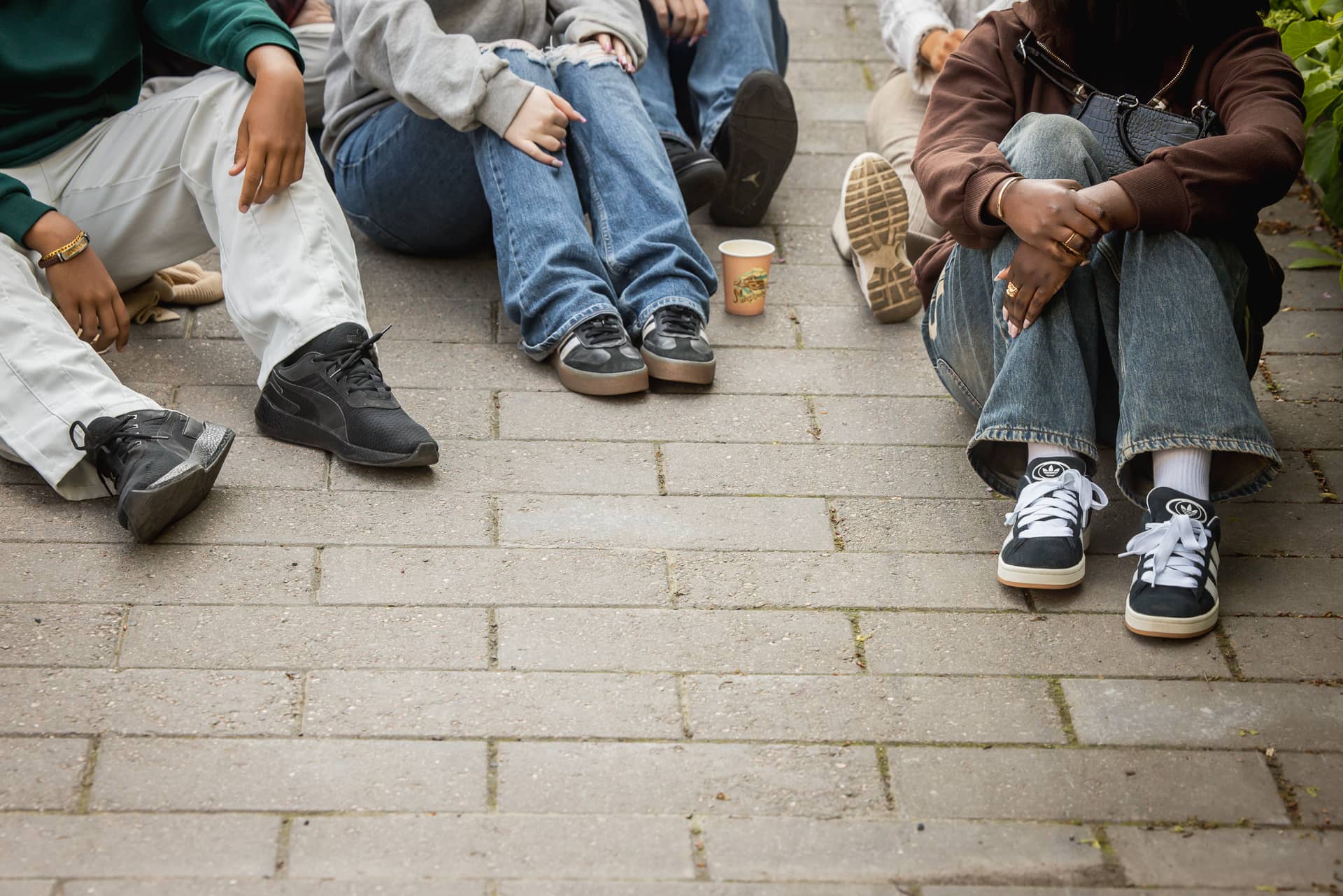 Nuorten jalkoja kuvattuna. Nuoret istumassa maassa.