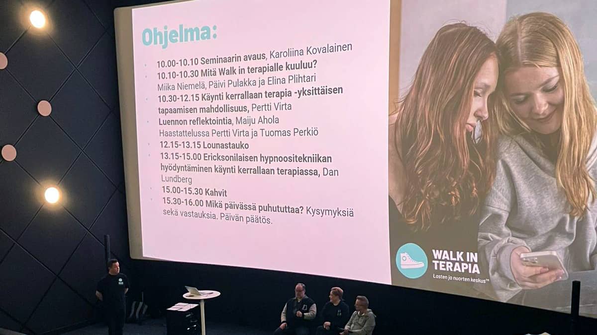 Walk in terapia -seminaarin lavalla juontaja ja panelistit.